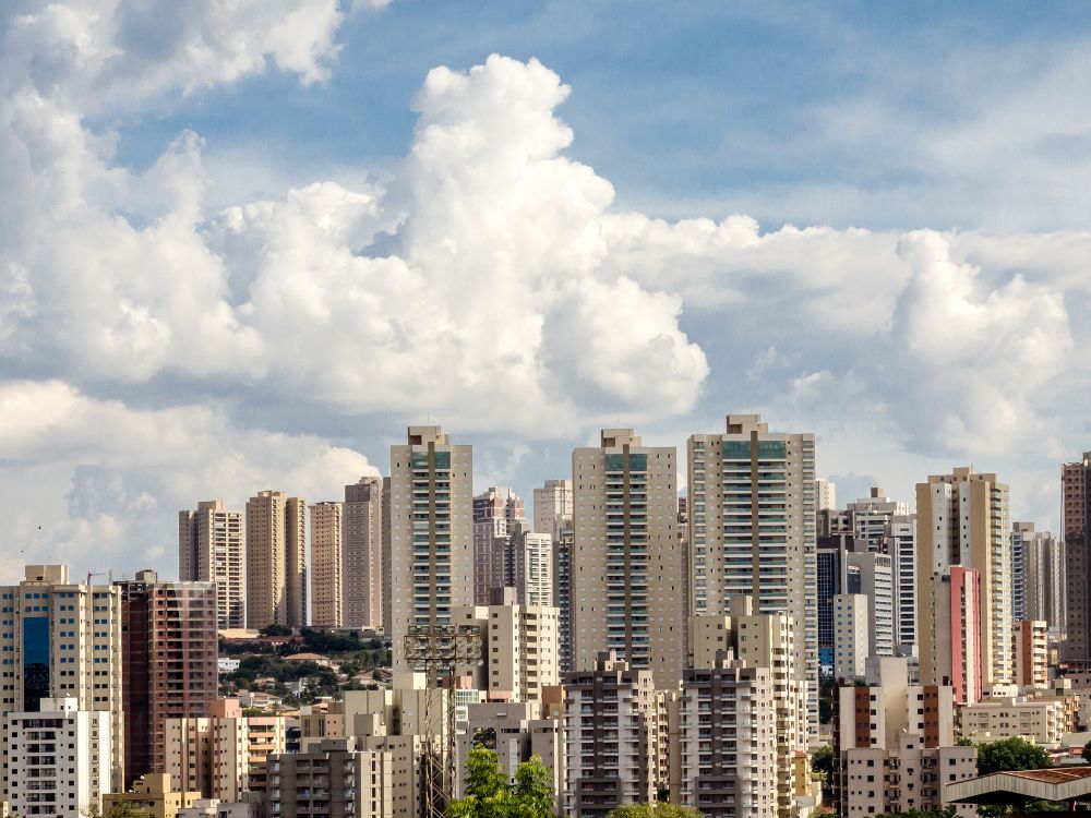 Vista urbana de Ribeirão Preto com prédios residenciais e comerciais sob céu com nuvens, destacando o crescimento da cidade e sua estrutura urbana.